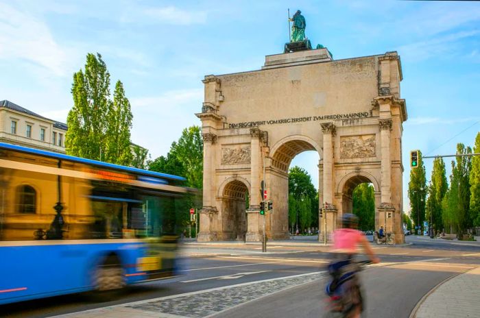 A cyclist and bus in a blur as they rush past an ornamental arch in the city