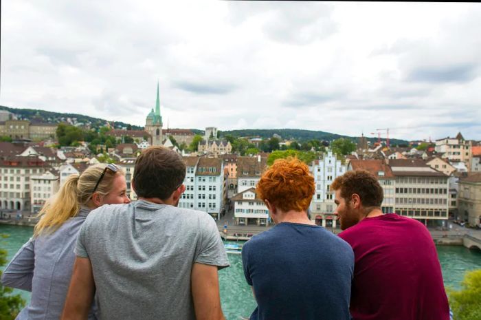 A group of four young friends, including a blonde woman and three guys (one with red hair), enjoying the view from the terrace of Lindenhof in Zurich.