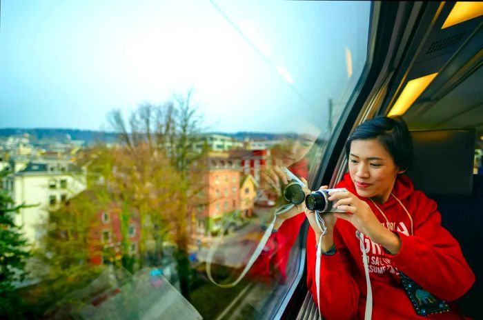 An East Asian woman captures the scenery through the window of an SBB train in Zurich, Switzerland