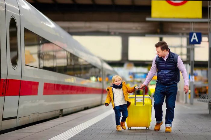 A smiling young boy and his father waiting for an express train at the railway station platform