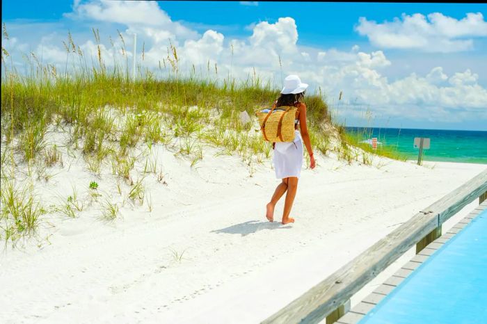 A woman in a white bikini enjoying the pristine sandy beach and emerald waters of the Gulf of Mexico, complete with a hat, drink, and beach bag.