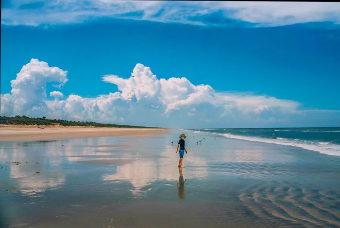 A boy stands on a wet stretch of sand at New Smyrna Beach, located near Orlando, Florida