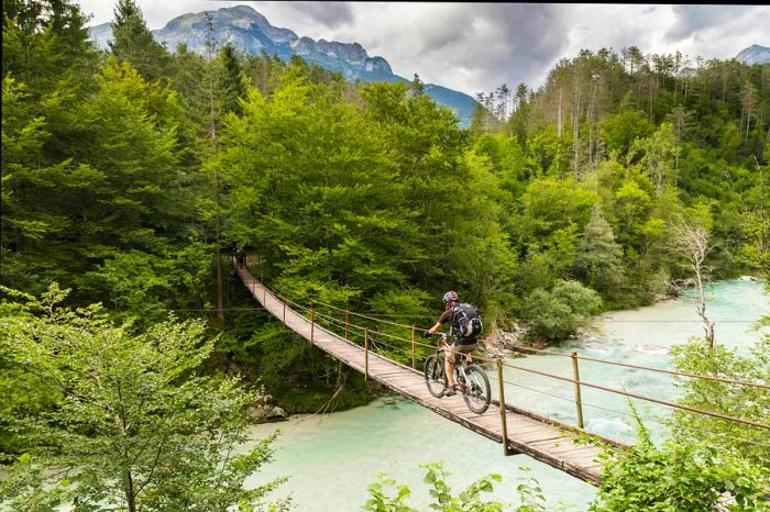 A mountain biker traverses a suspension bridge over the Soča River in Slovenia's Julian Alps.