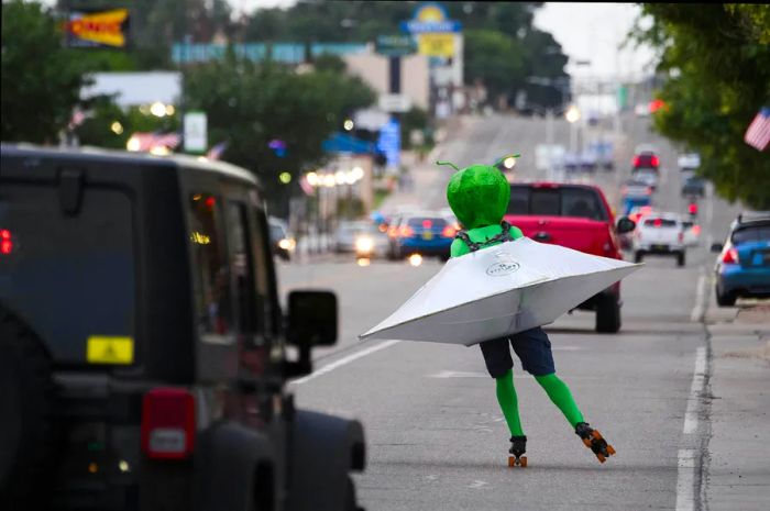 An individual in an alien costume roller-skates through traffic on Main Street during the UFO Festival in Roswell, New Mexico, on July 2, 2021.