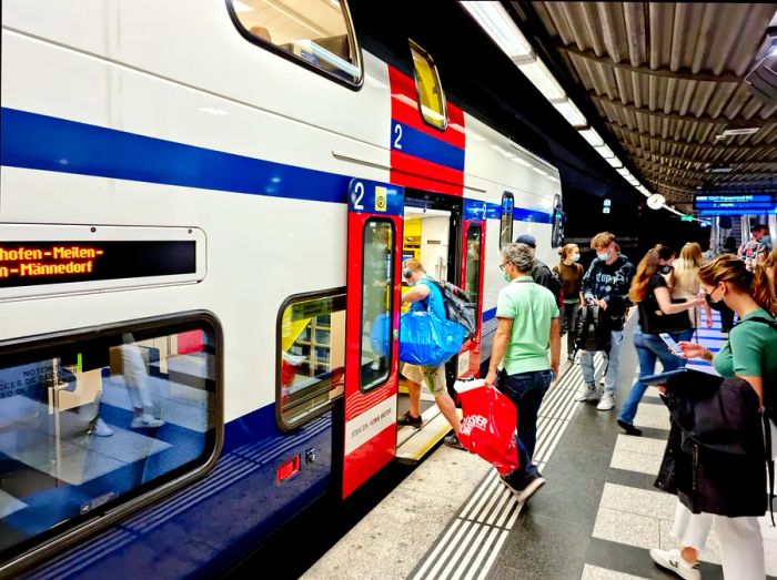 An image of Zurich Main Railway Station featuring the underground level, with an S-Bahn service and several passengers boarding the train.