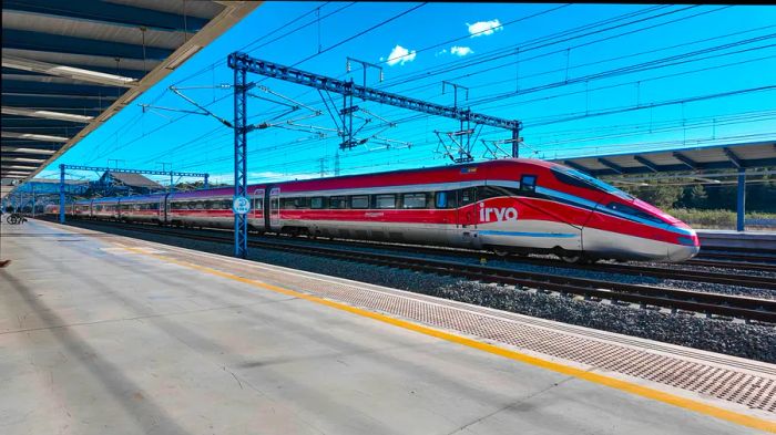 A crimson train rushes through a station