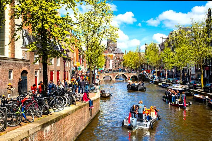 Crowded canals of Amsterdam buzzing with celebrations on King's Day, with many revelers on boats