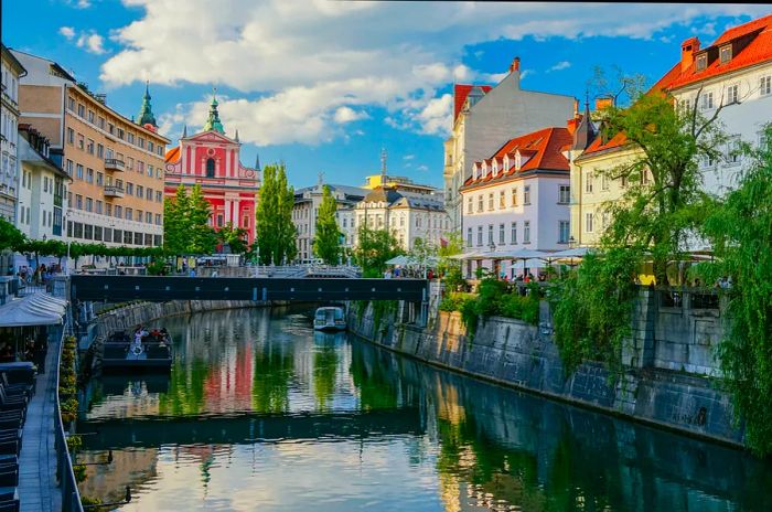 A river flows through the heart of the city, alongside a church with a charming pink facade.