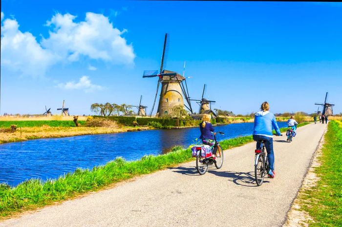 A mother and her children ride bicycles past the windmills at Kinderdijk.