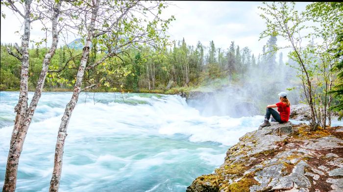 A woman enjoys the breathtaking view of Tanalian Falls in Lake Clark National Park and Preserve, Alaska