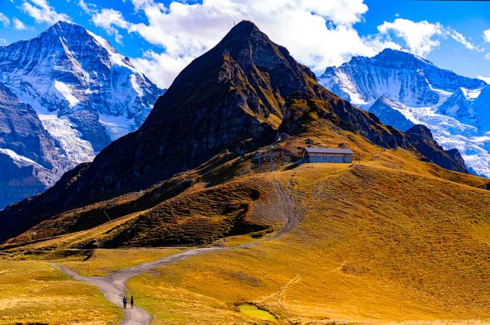 Two hikers trek along a trail leading to a mountain summit