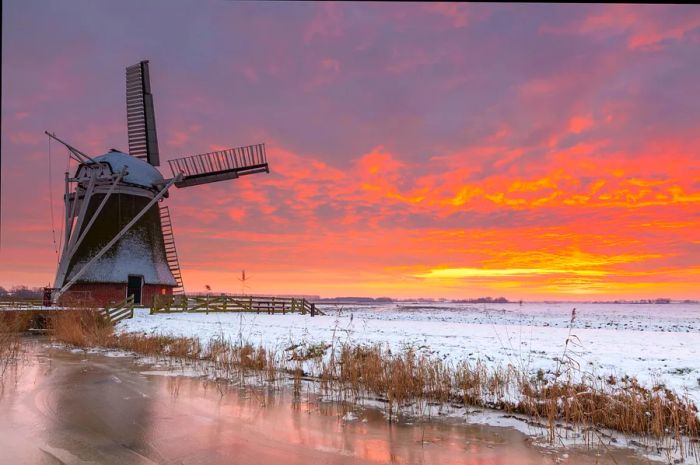 A winter sunset over the Meervogel windmill, with ice and snow in the foreground