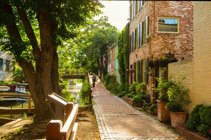 A man strolls past historic buildings along the C&O Canal in Georgetown, Washington, DC, USA.