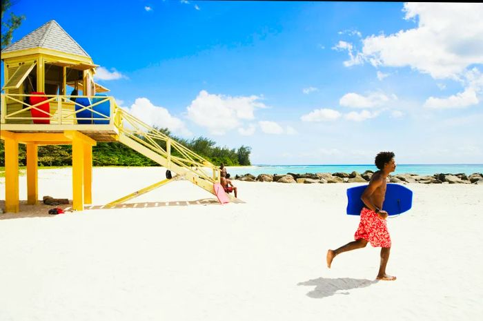 A bodyboarder rushes past a lifeguard station heading towards the waves