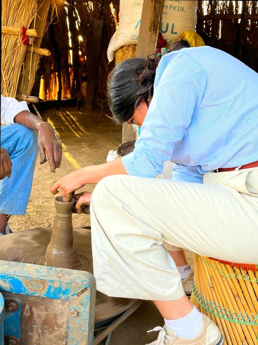 The writer experiments with pottery throwing during an outdoor class.