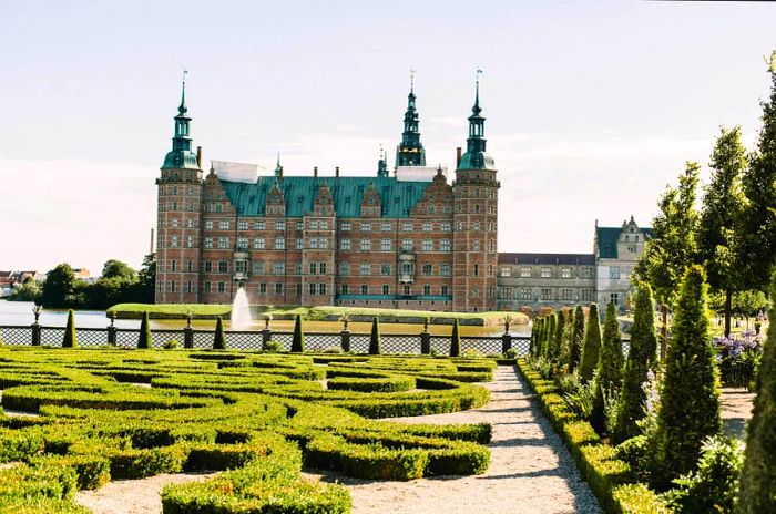 Frederiksborg Castle viewed from afar, surrounded by perfectly groomed gardens, located in Hillerod, Denmark.