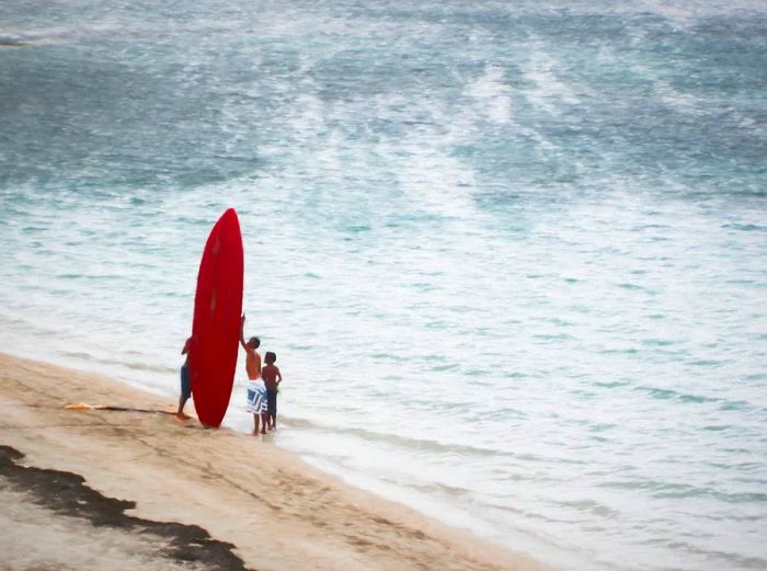 Children with a red surfboard enjoying the beach