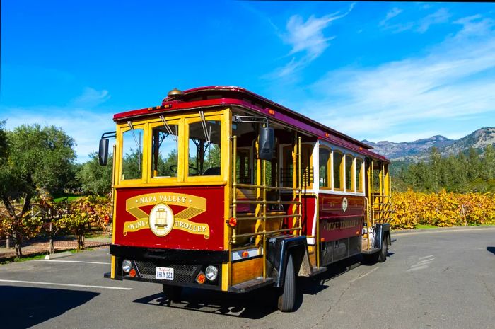 A cable car that has been adapted to operate on the road parked near a vineyard