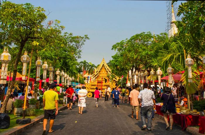 A crowd of people strolls towards Wat Phra Sing in Chiang Mai's Old City during the Songkran festival.