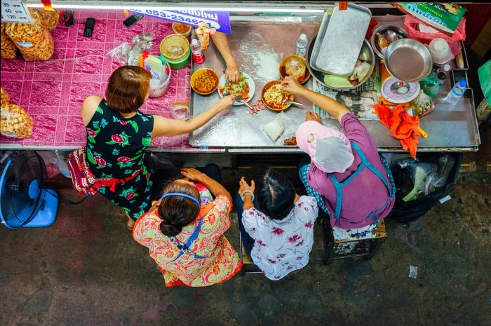 Aerial view of a group enjoying Thai cuisine for lunch at Warorot Market in Chiang Mai.