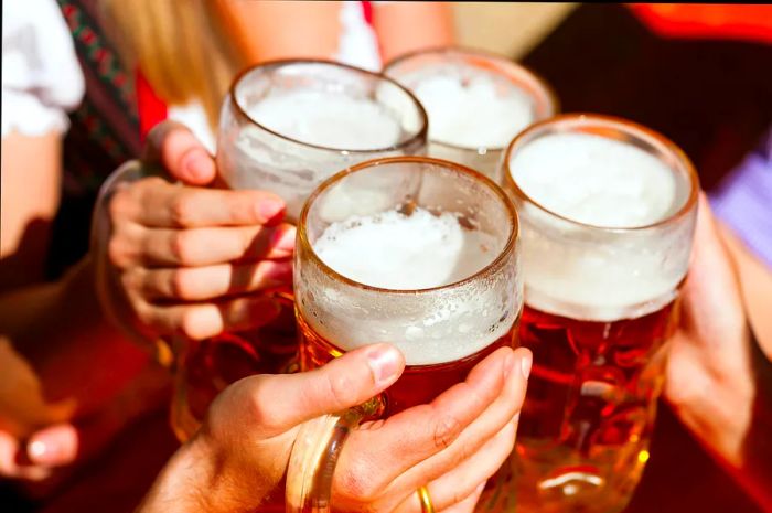 Four friends raising their beer steins in a beer garden