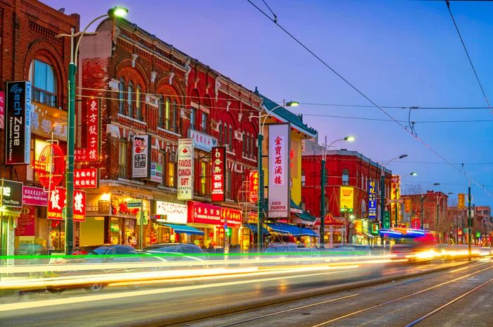 A nighttime street lined with shops offering Chinese food and products.