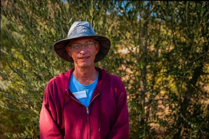 A man smiles for the camera beside a bush