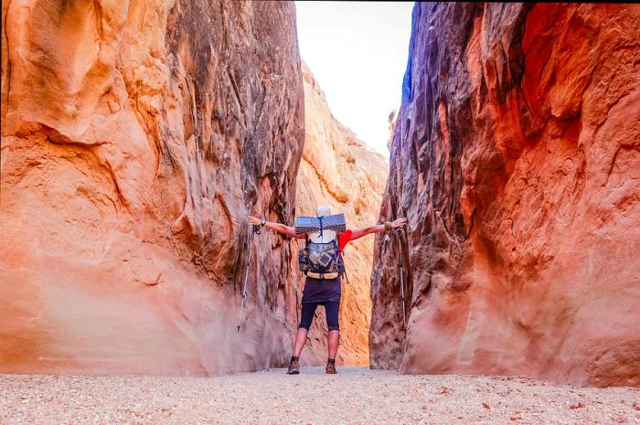 A backpacker navigates through a narrow canyon in Utah.