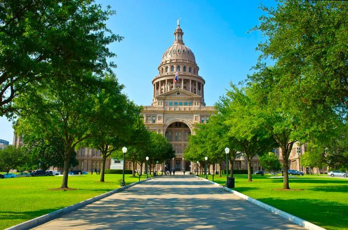 Visitors stroll along a path leading to a majestic domed government building.