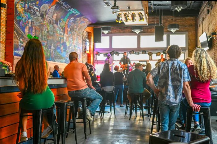 Crowds gather at a bar to enjoy live music performed by a band on stage.