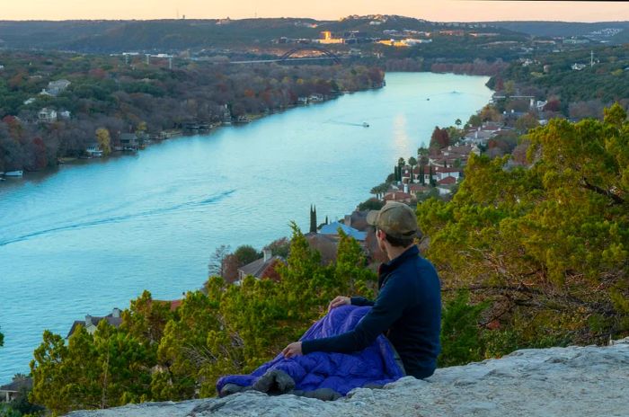 A man enjoys the sunset from Mount Bonnell in Austin.