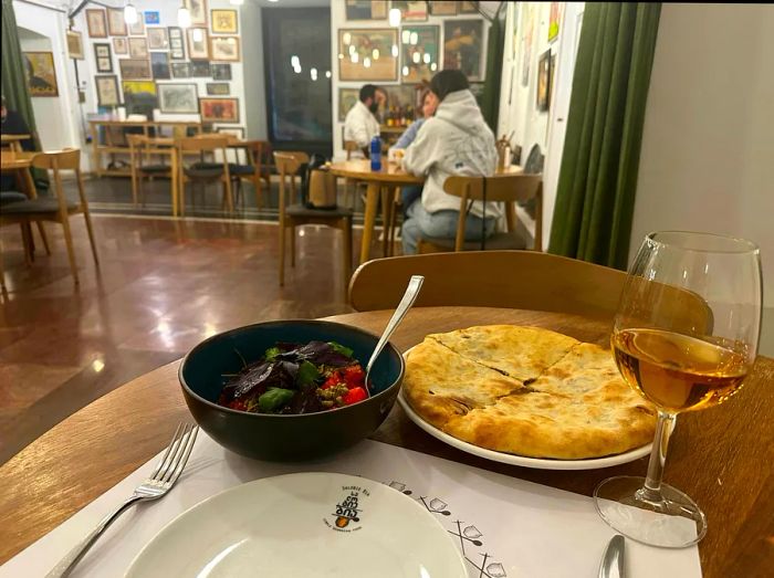 A table set with a glass of wine, bread, and a fresh tomato salad.