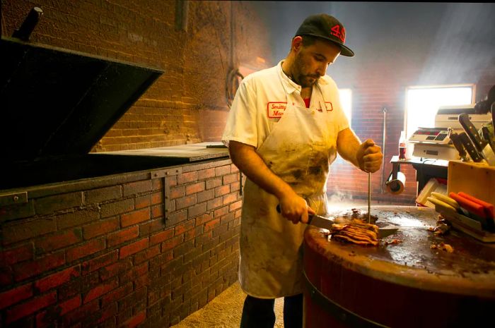 A staff member carves barbecue for a customer at Smitty's Market in Lockhart, Texas