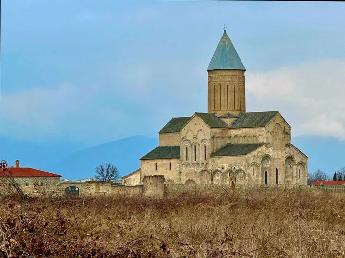 A grand stone cathedral rises before the shaded mountains.