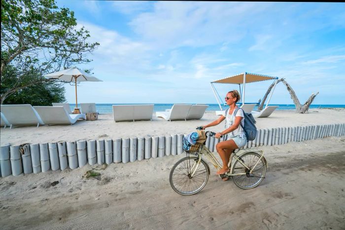 A cheerful woman cycling along the beach in the morning.