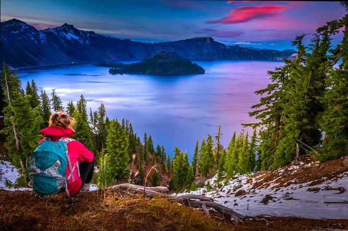 A hiker relaxes on a ridge with a view of a lake