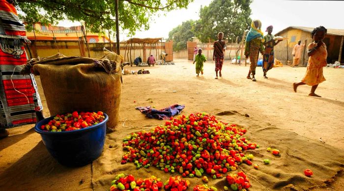 People stroll past a market stall filled with fresh fruit