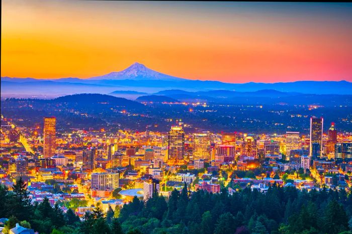 A city skyline illuminated at dusk, with a majestic mountain peak visible in the distance.