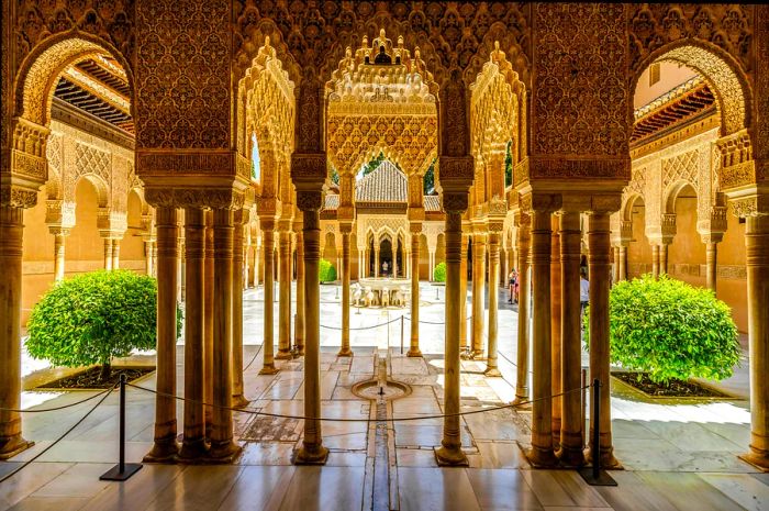 Many columns adorned with intricate carvings surround a stunning courtyard.