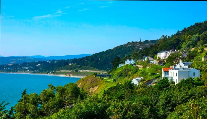 A train traverses a village by the sea's edge