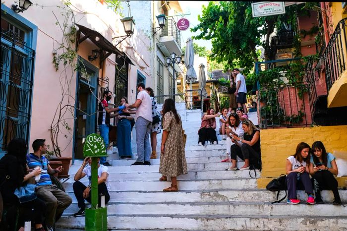 Tourists and locals gather on the white steps outside a hillside cafe.