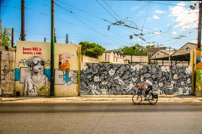 A cyclist rides past vibrant graffiti in central Athens.