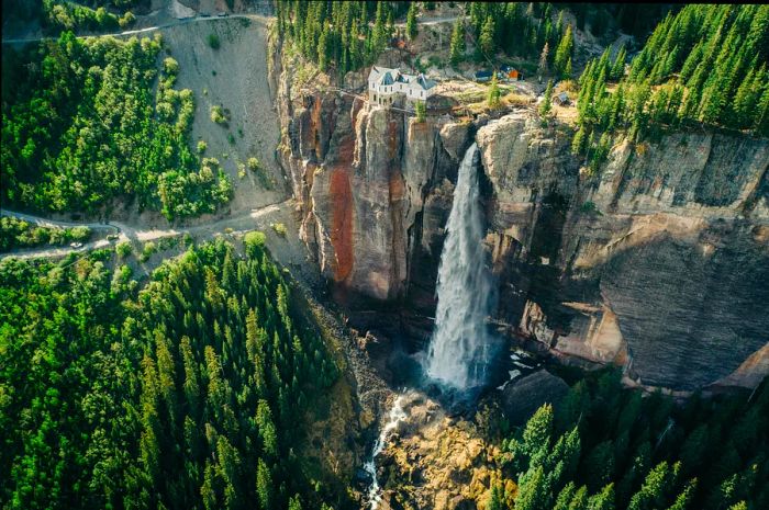 A waterfall plunges into a wooded canyon