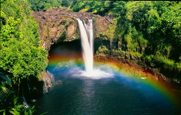 Rainbows form in the mist at the base of a waterfall