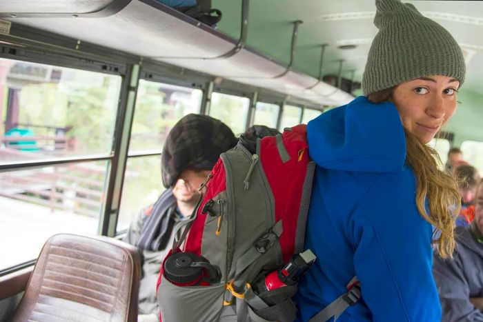 A young woman with a backpack riding the bus in Denali National Park, Alaska.