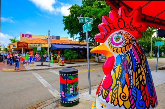 Street art and a vibrant mural-covered cockerel sculpture on a sunny day