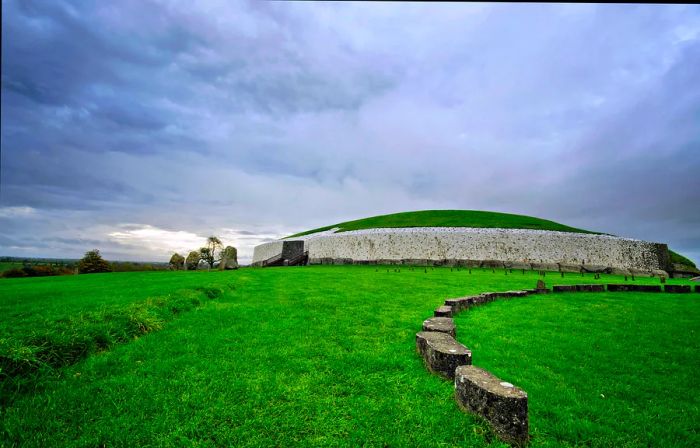 A large burial mound nestled in lush green countryside