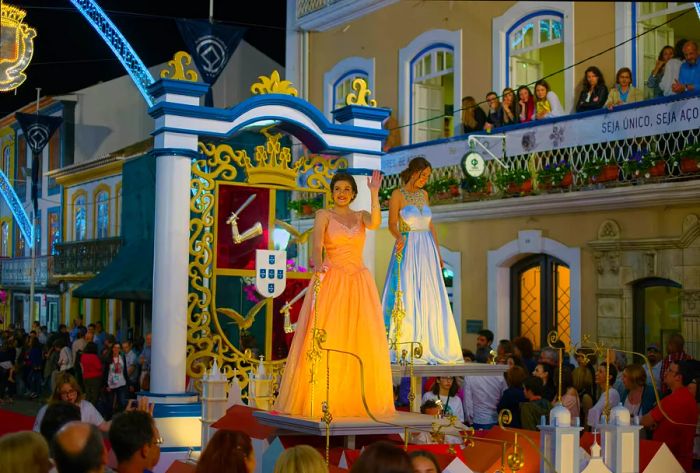 Spectators watch as two women in historical gowns grace a float during a parade in Angra do Heroismo, Terceira, for the Sanjoaninas celebrations.