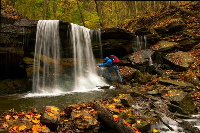 A male hiker stands near Lower Tews Falls along the Bruce Trail in Hamilton, Ontario, Canada