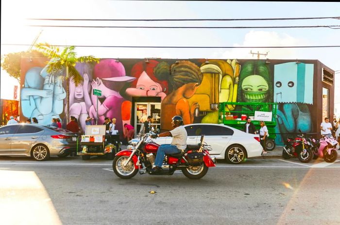 Traffic flows past vibrant street art in Miami's Wynwood District.